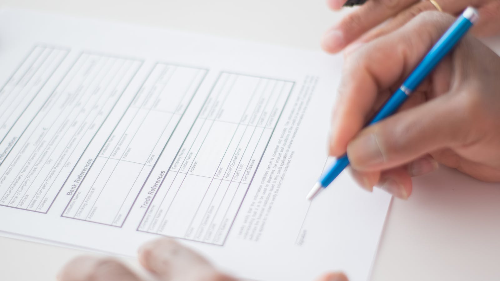 A service contractor reviewing a written contract with a customer at a kitchen table, with both signatures visible at the bottom.