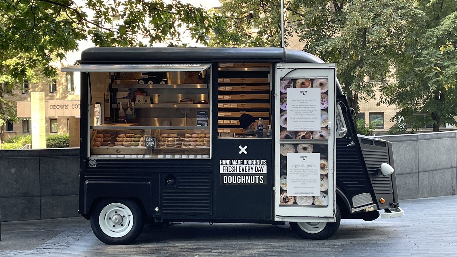 A food truck parked at a city event with customers ordering at the service window.