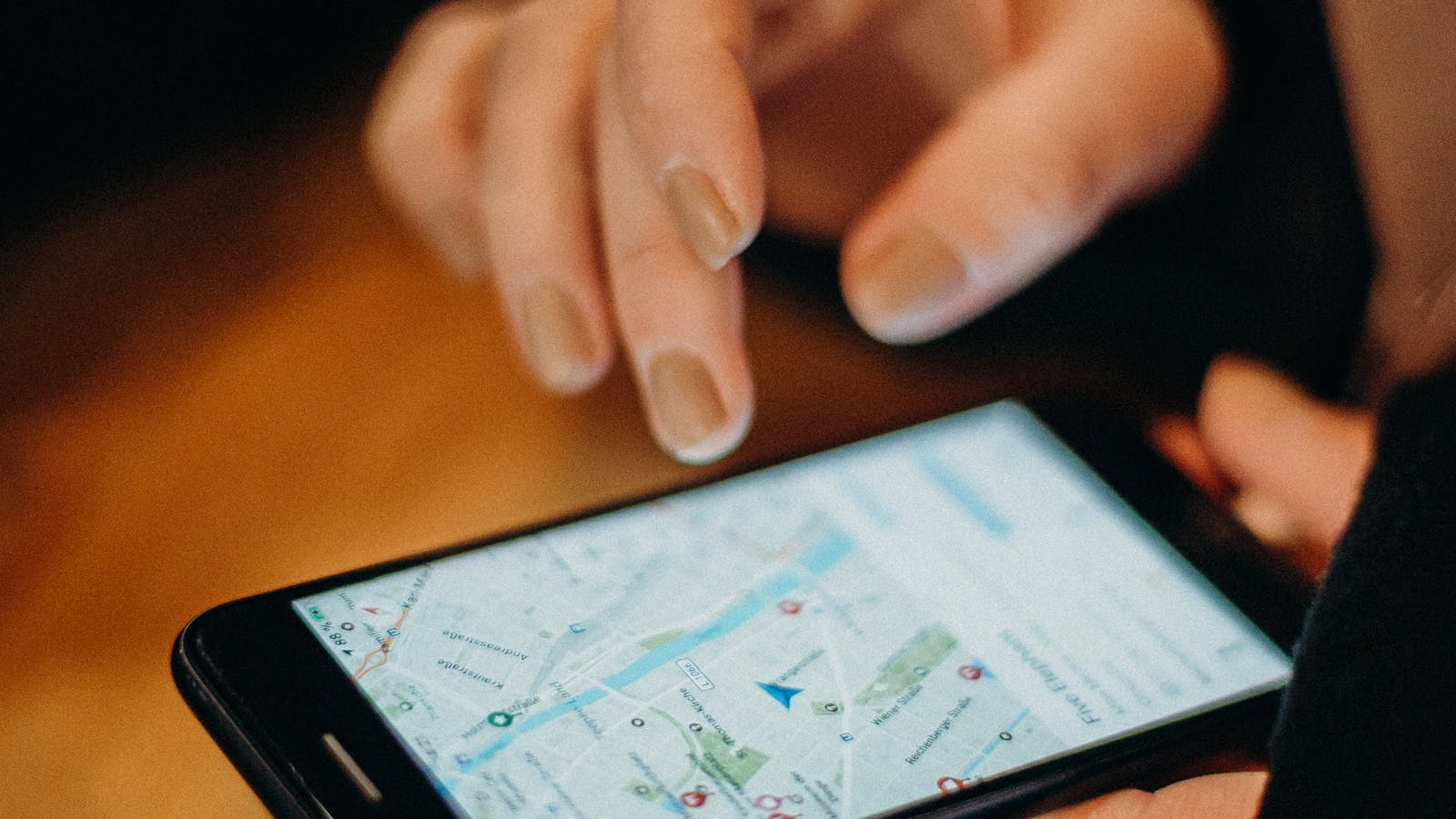 A small business owner reviewing their Google Business Profile listing on a smartphone with a laptop open to Google Maps in the background.