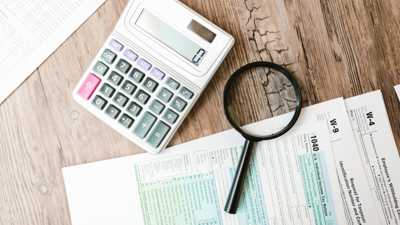 An SBA loan application document on a desk with a calculator, pen, and a small business owner's hands reviewing the paperwork.
