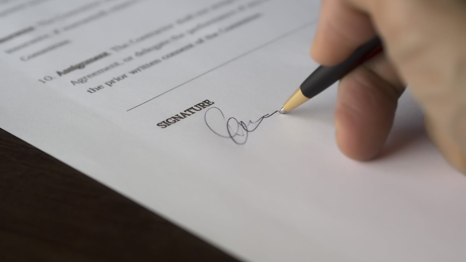 A service contractor signing employment paperwork at a desk with a calculator, employment forms, and a coffee — capturing the moment of formalizing a first hire.