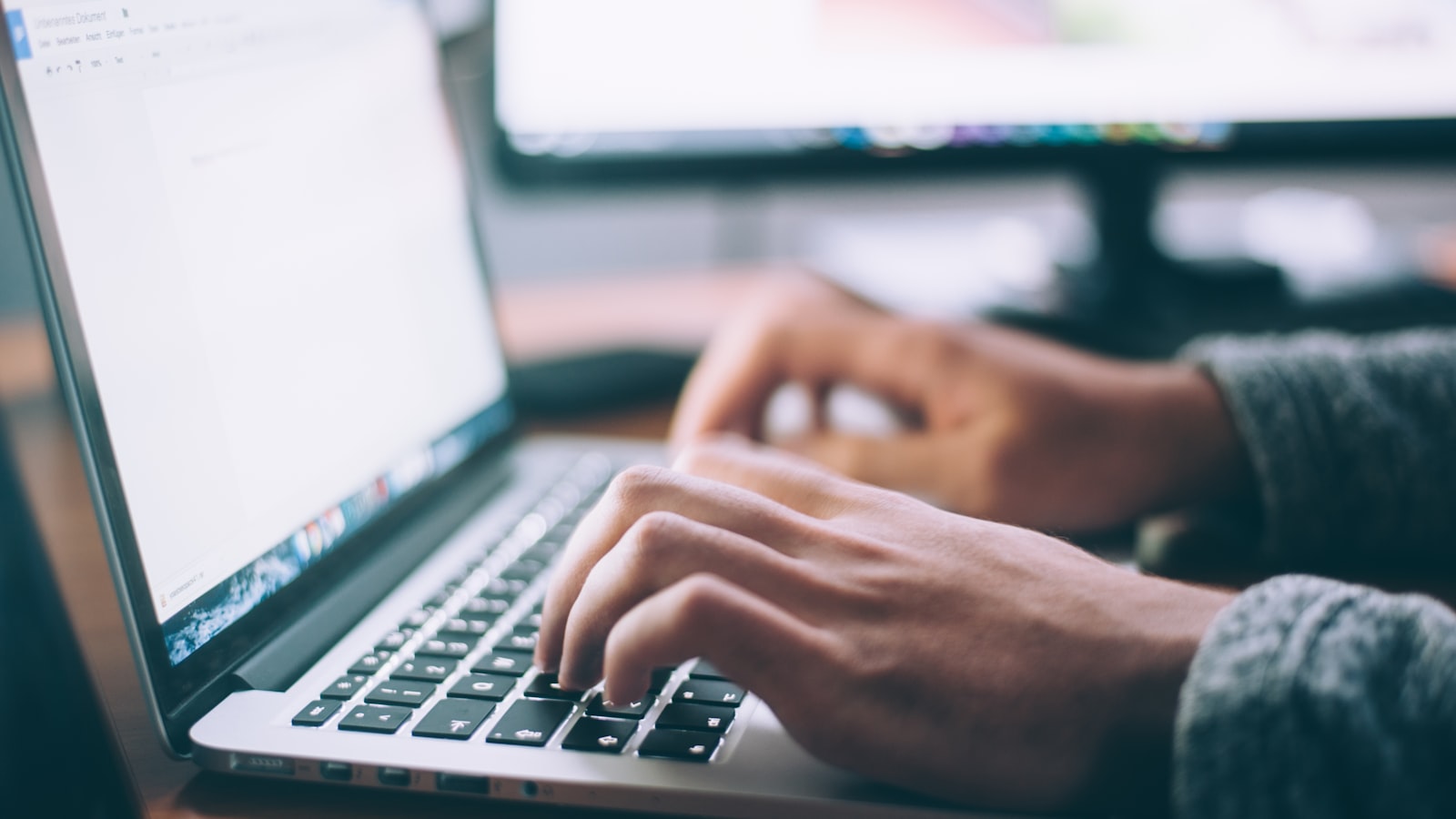 A laptop, notebook, and coffee on a wooden desk — the lean office setup most service businesses actually need before buying software.