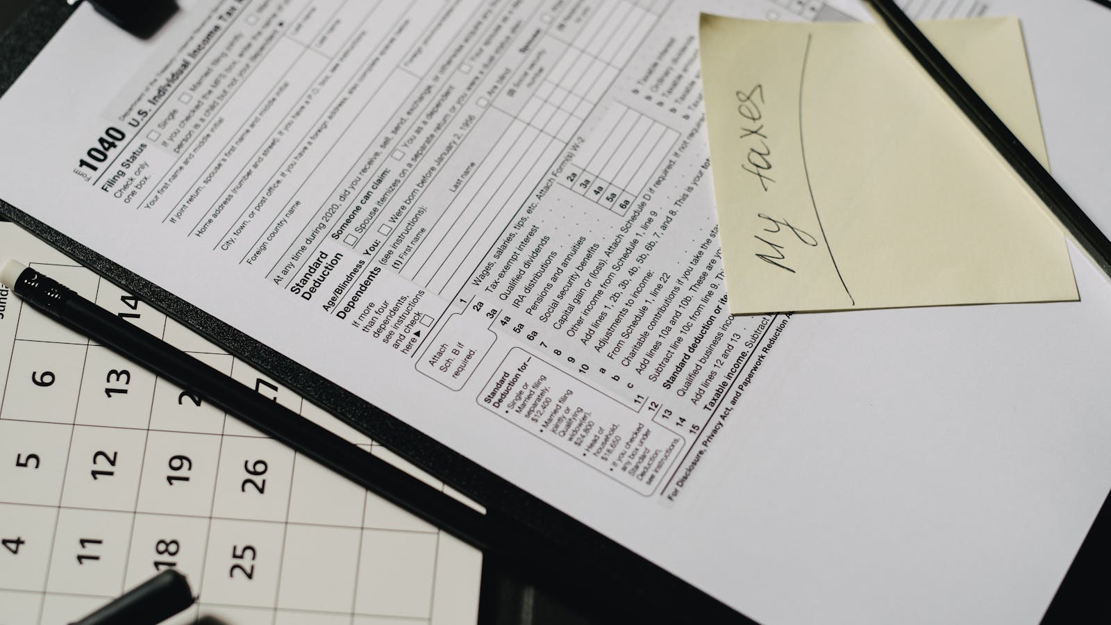 A self-employed contractor reviewing tax forms and a calculator at a desk during tax season, representing the annual tax planning ritual every service business owner faces.