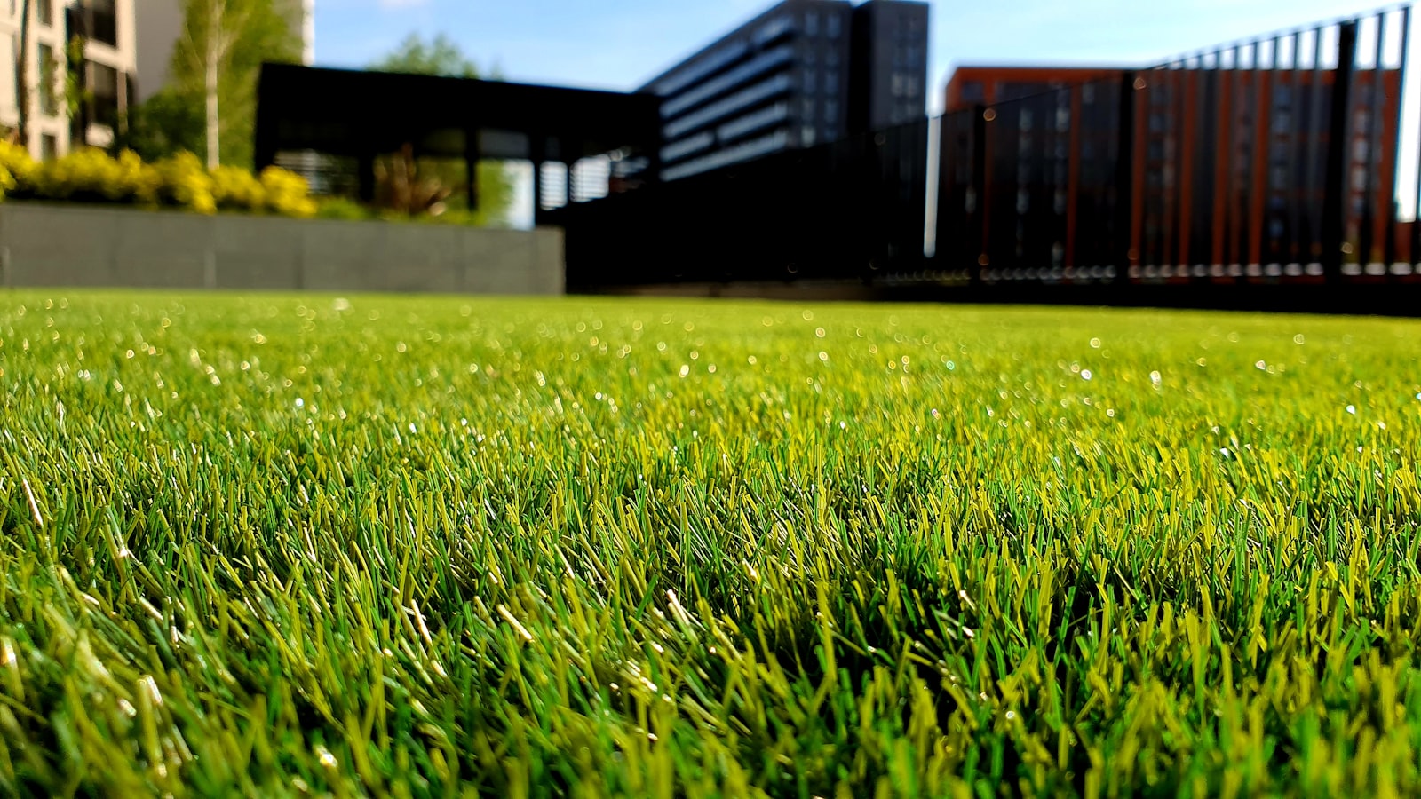 A landscaper using a commercial zero-turn mower on a manicured residential lawn with trimmed edges visible.